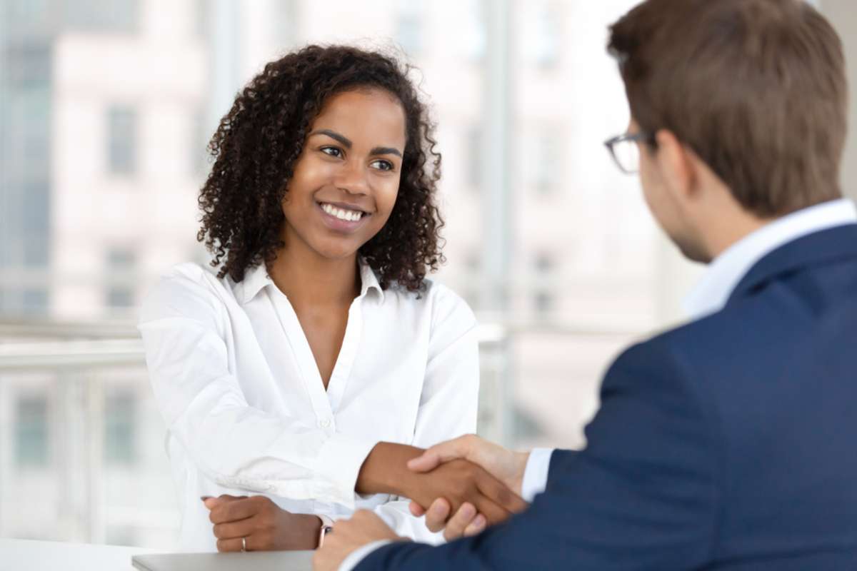 Smiling african female hr manager handshake hire male candidate at job