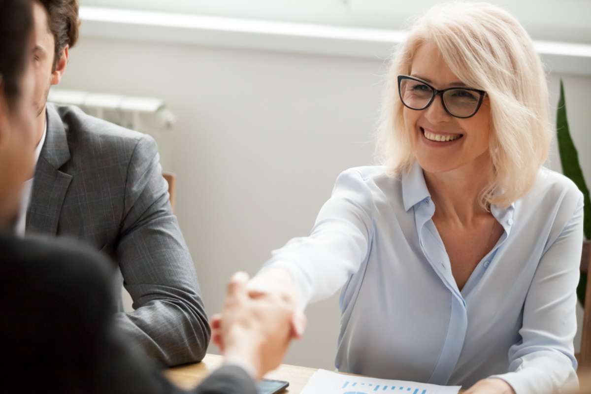 Smiling attractive mature businesswoman handshaking businessman