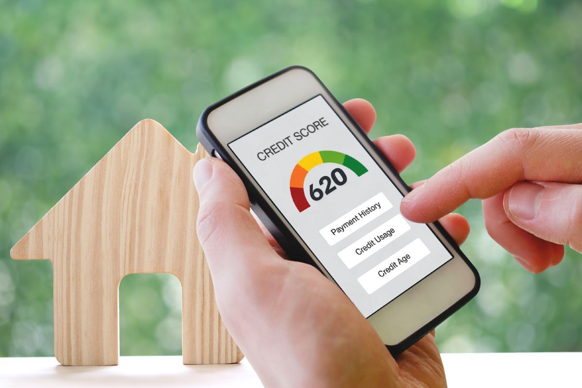 Smartphone displaying a 620 credit score beside a wooden house icon, representing the minimum score needed for a conventional loan in Texas.